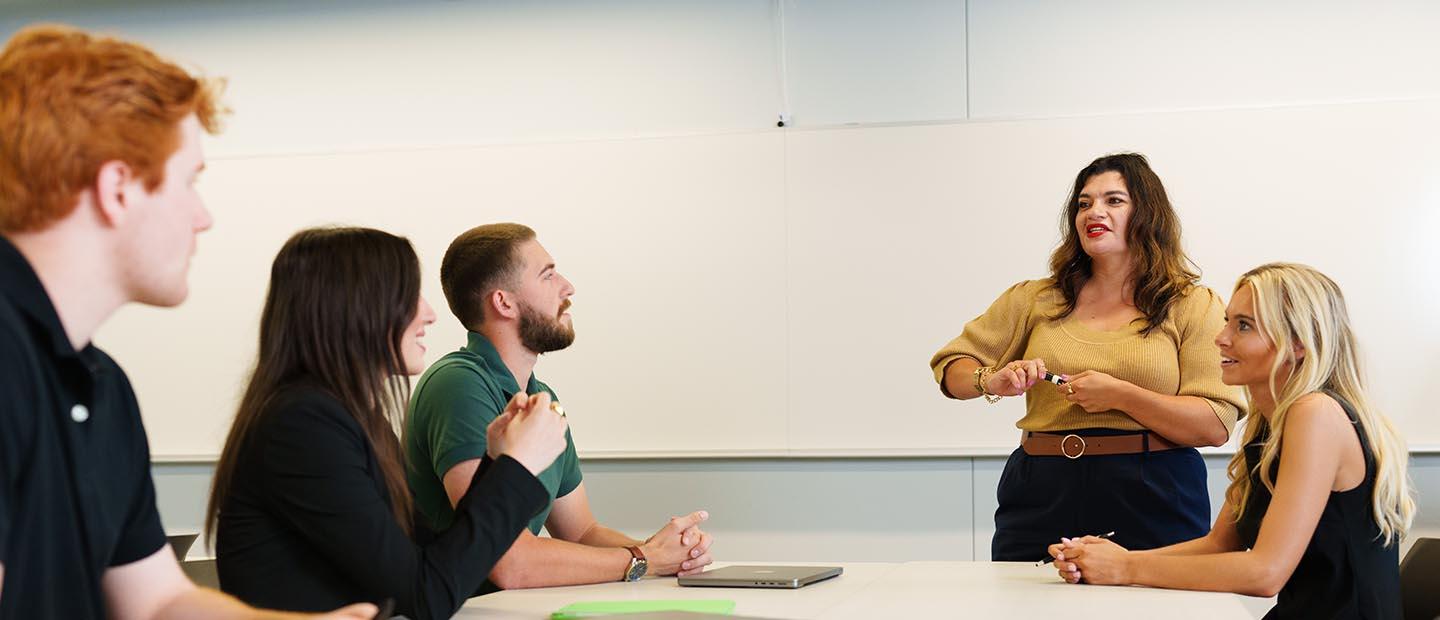 A professor standing in front of a table of students